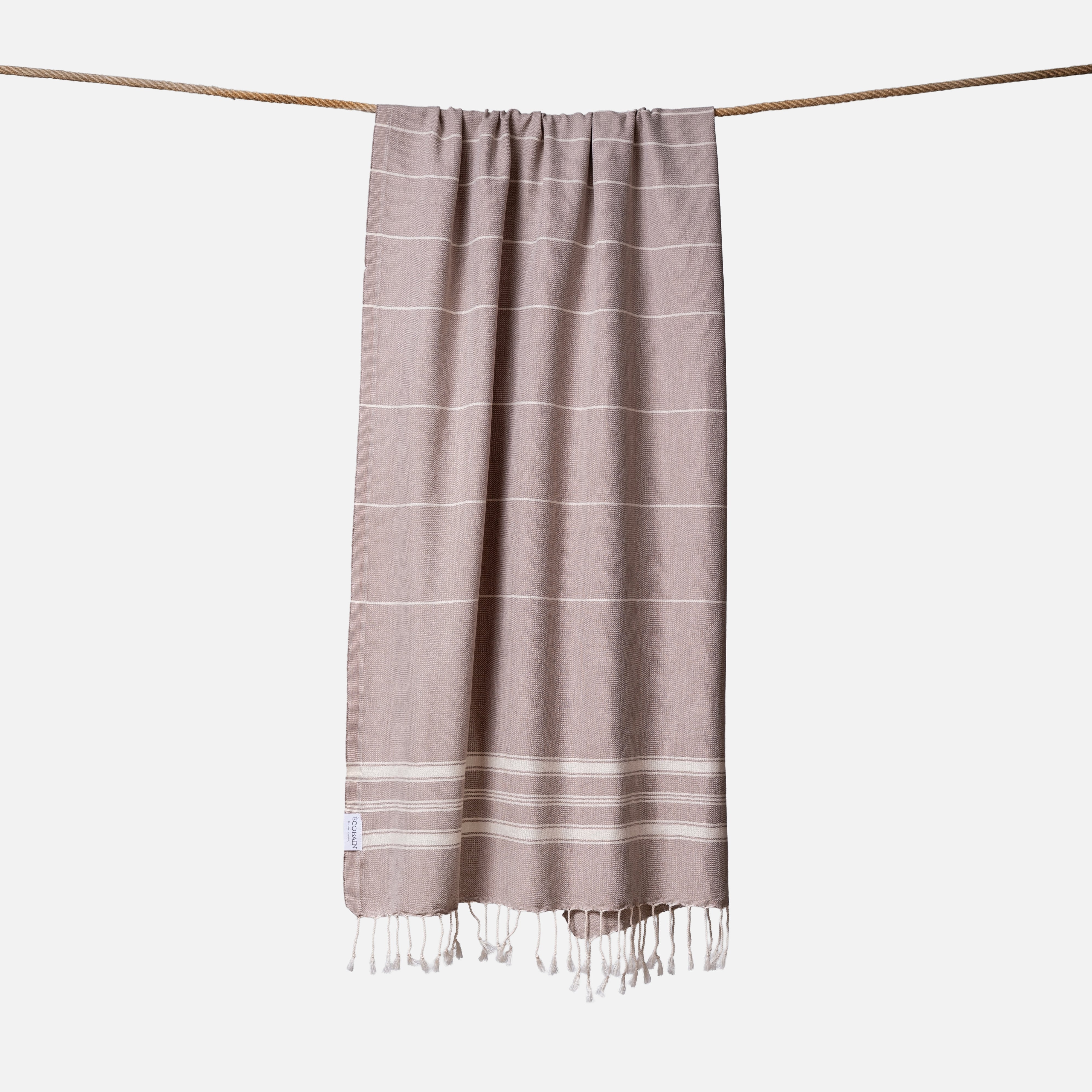 Extragroßes Ecobain Strandlaken der Liberty Series im natürlichen Taupeton Dusty Pier. Das platzsparende Pestemal in 100x200 cm wird liebevoll gerollt mit originalem Hang Tag geliefert und ist die ideale nachhaltige Geschenkidee für Outdoor-Enthusiasten. Ein sandfreies Reisehandtuch aus pestizidfreiem Anbau, das auf jeder Camping-Tour oder am See schweres Frottee ersetzt und mit seiner erdigen Ästhetik überzeugt.