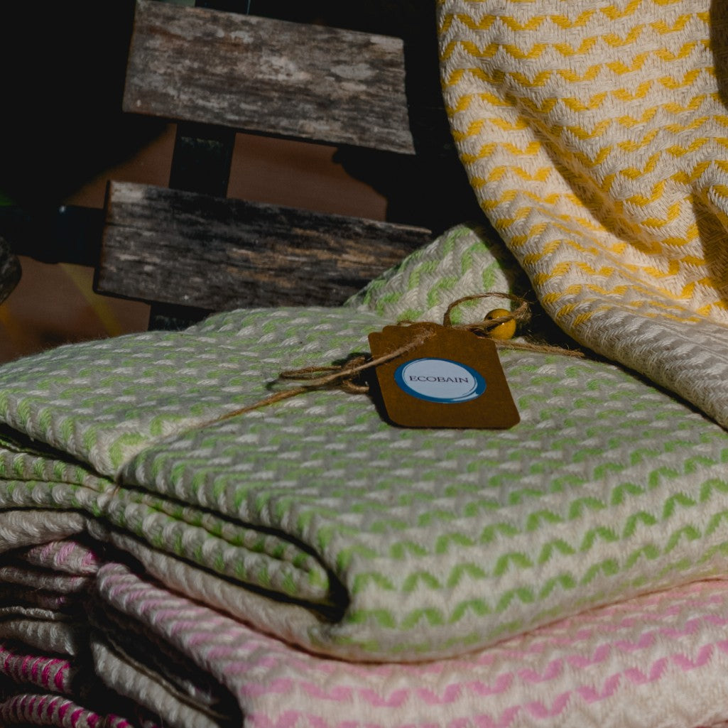 Ein frisches, limettengrünes Ecobain Gordion Towel (Lime Green), das an einer weißen, klassischen Holztür hängt und das Muster sowie die Fransen zeigt.