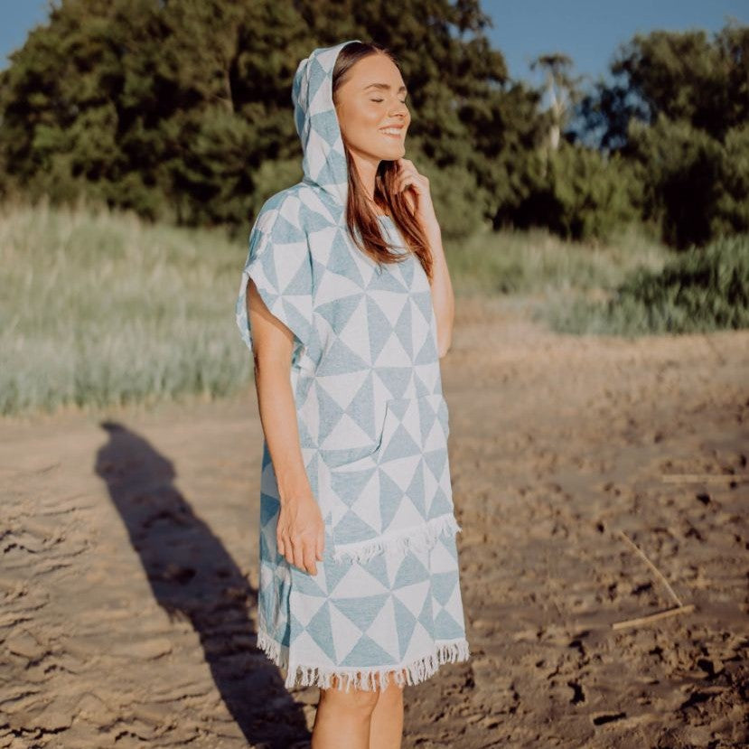Vorderansicht einer Person im Ecobain Poncho Symique in Blue Hawaii, die den lockeren Schnitt und die praktische Bauchtasche präsentiert.