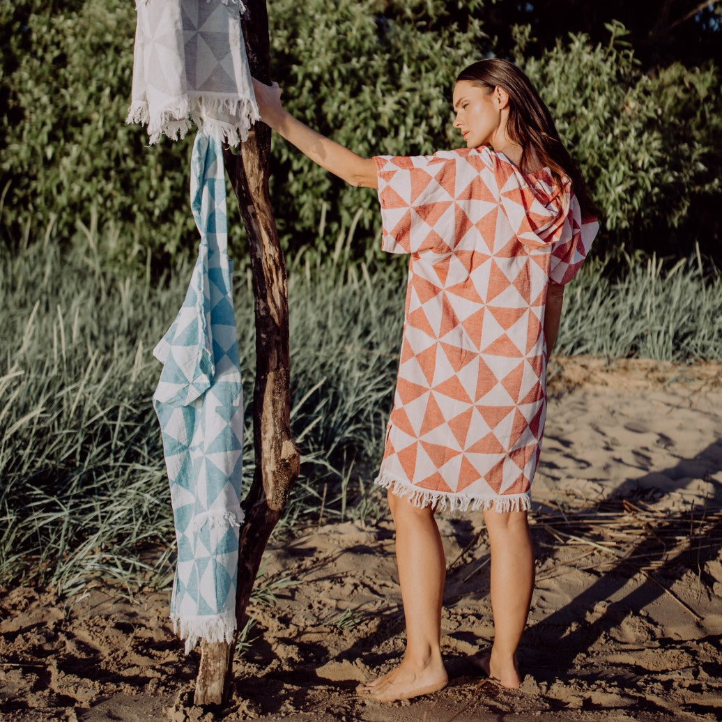 Rückansicht einer Person, die den bequemen Ecobain Poncho Symique in Blue Hawaii in der Natur trägt, Fokus auf den weichen Fall des Stoffes.