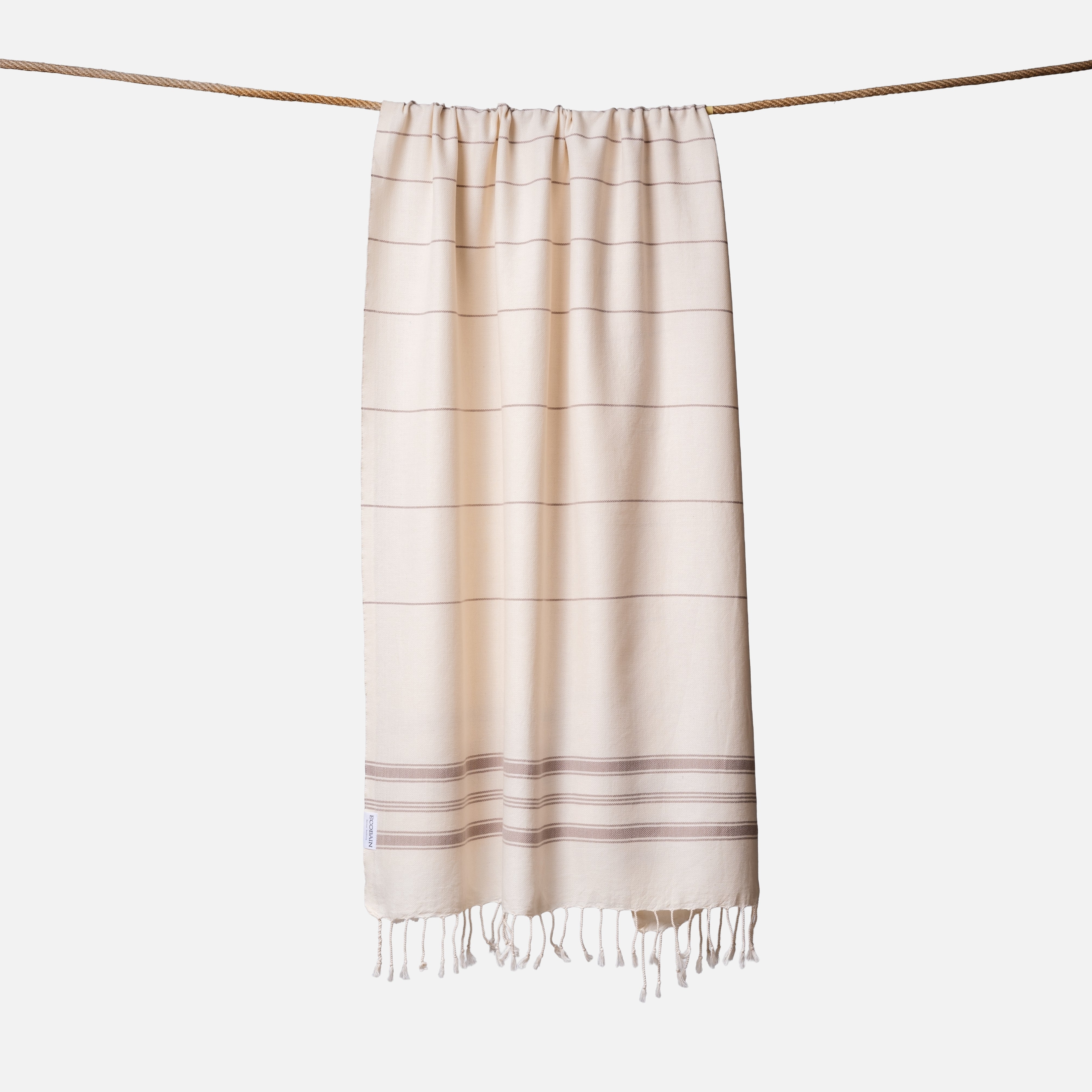 Extragroßes Ecobain Strandlaken der Liberty Series in natürlichem Ecru und Taupe. Das platzsparende Pestemal in 100x200 cm wird liebevoll gerollt mit originalem Hang Tag geliefert und ist die perfekte nachhaltige Geschenkidee für Outdoor-Fans und Camper. Ein absolut sandfreies Reisehandtuch aus pestizidfreiem Anbau, das auf jeder Picknickdecke oder im Van schweres Frottee ersetzt und mit seiner hellen Ästhetik überzeugt.